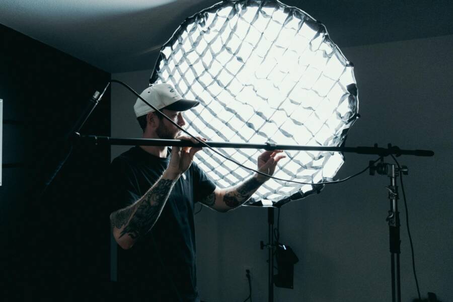 Cameraman adjusts lighting equipment on film set. Behind-the-scenes production view.