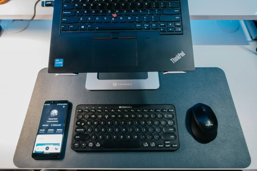 A sleek workspace featuring a laptop, Bluetooth keyboard, smartphone, and mouse for productivity