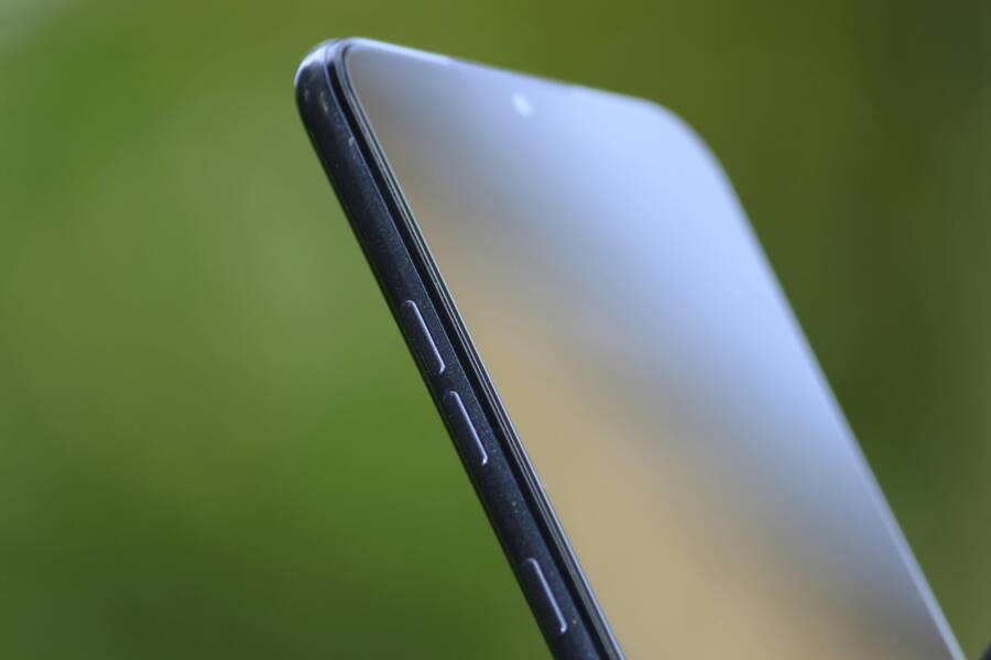 Detailed close-up of sleek smartphone edge with buttons against green background.