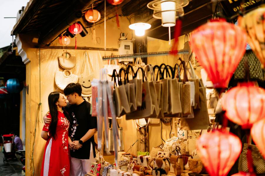 An Asian couple in love shares a moment while shopping at an illuminated night market.