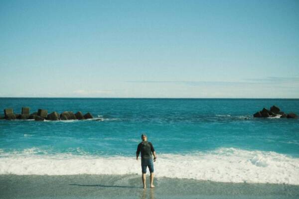 A man stands on a serene beach in Hualien, Taiwan, with ocean waves crashing nearby.