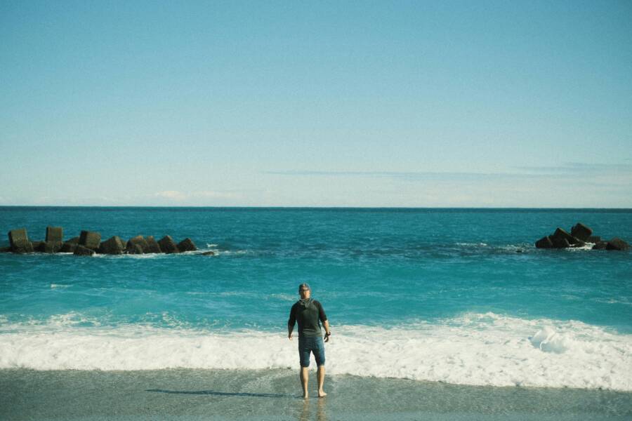 A man stands on a serene beach in Hualien, Taiwan, with ocean waves crashing nearby.