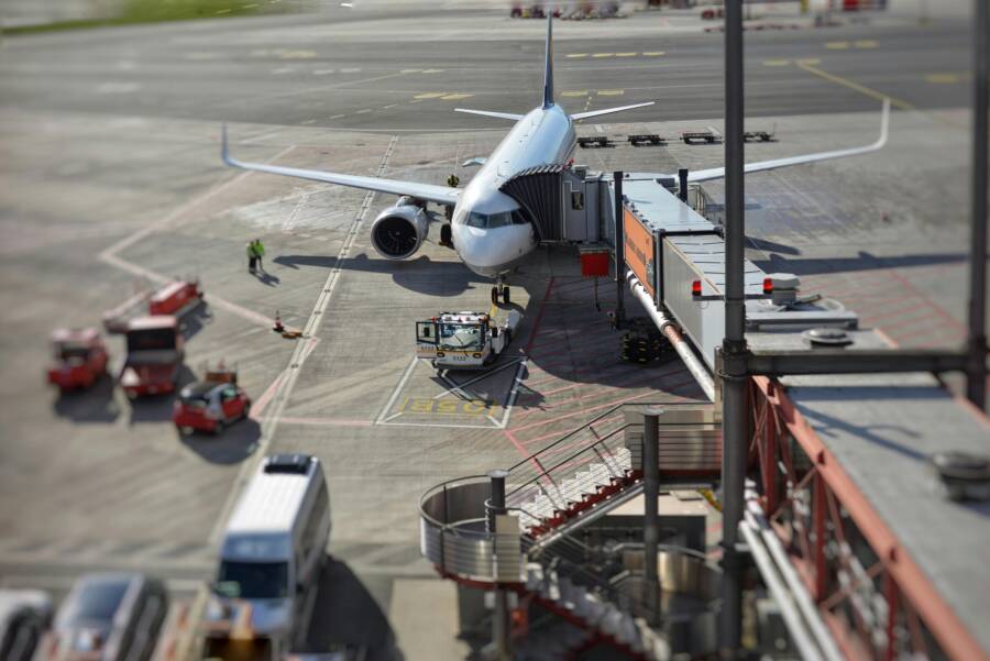 A bustling airport scene with an airplane on the tarmac being prepared for departure