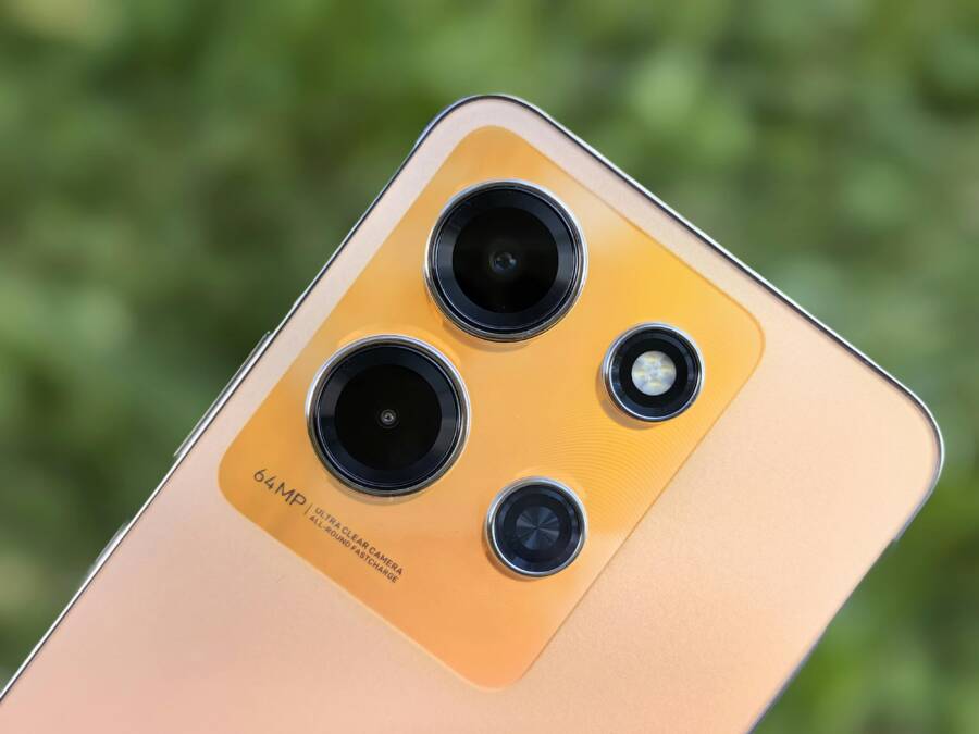 Detailed close-up of a modern smartphone camera lens array against a blurred green background.