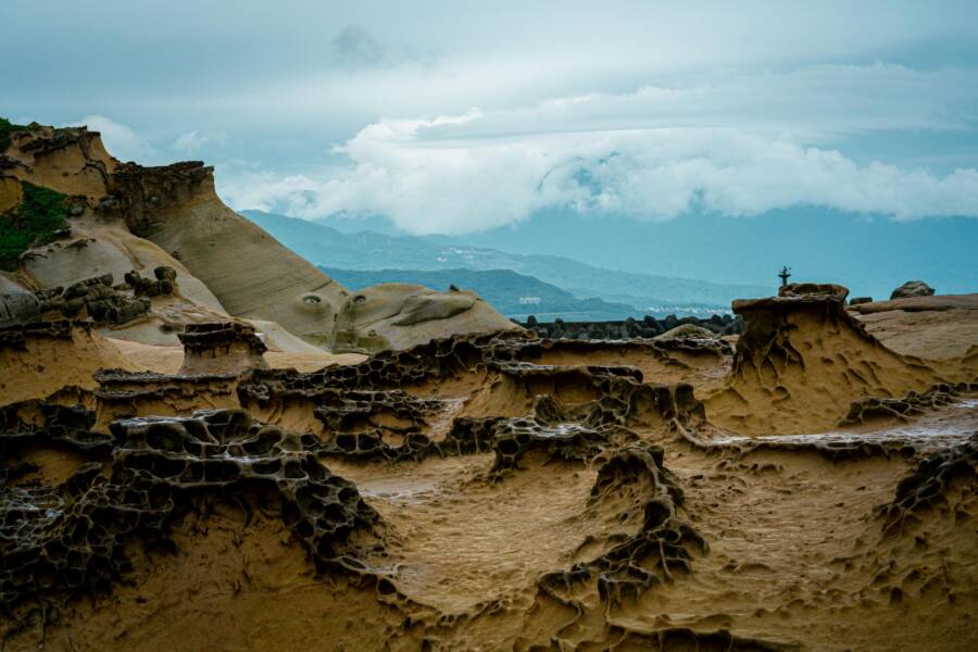 Captivating rock formations at Yehliu Geopark in Taiwan with a mountainous backdrop.
