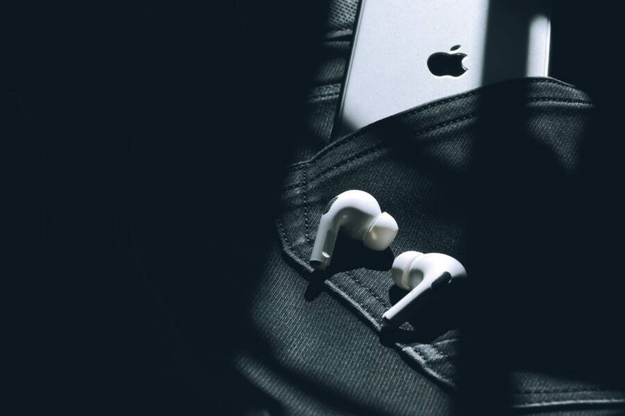 Wireless earbuds and a smartphone in a sunlit pocket, showcasing modern technology