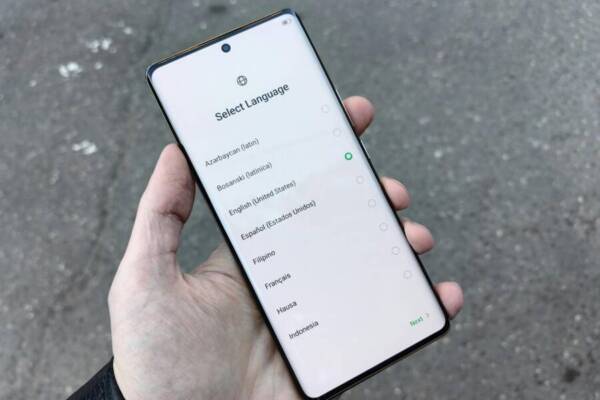 A close-up of a hand holding a smartphone showing a language selection screen outdoors in Moscow