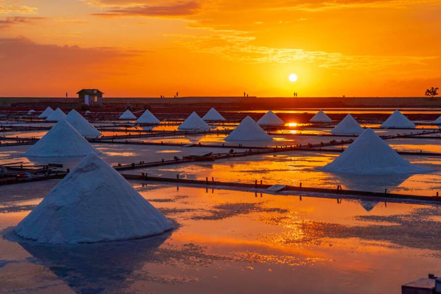 Captivating sunset view of Jingzaijiao salt fields, Tainan, Taiwan, with silhouettes and reflections.