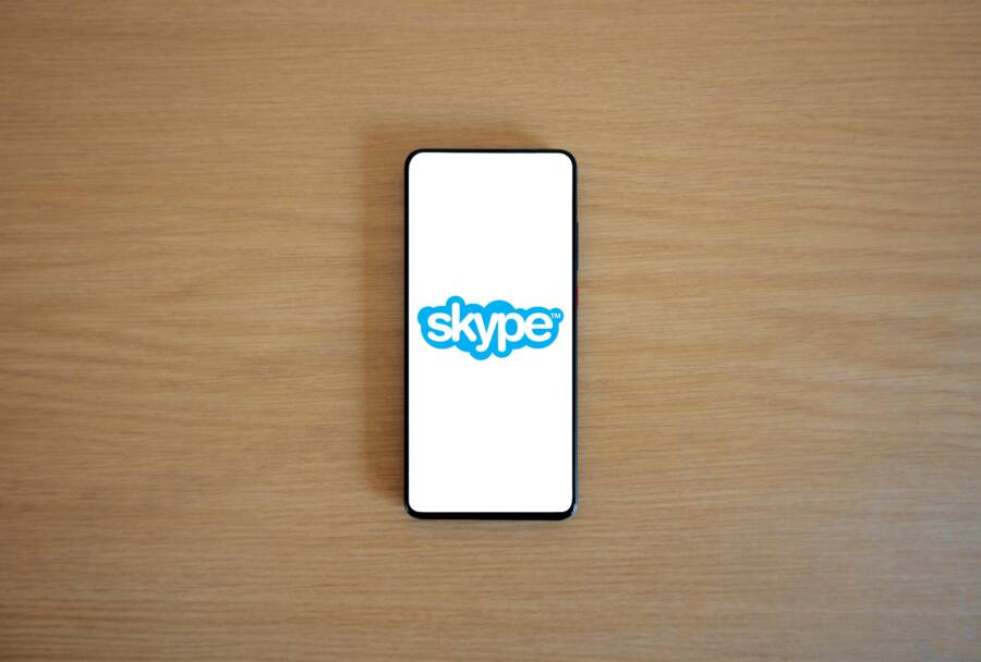 A smartphone top view showing Skype logo on screen, placed on a wooden surface