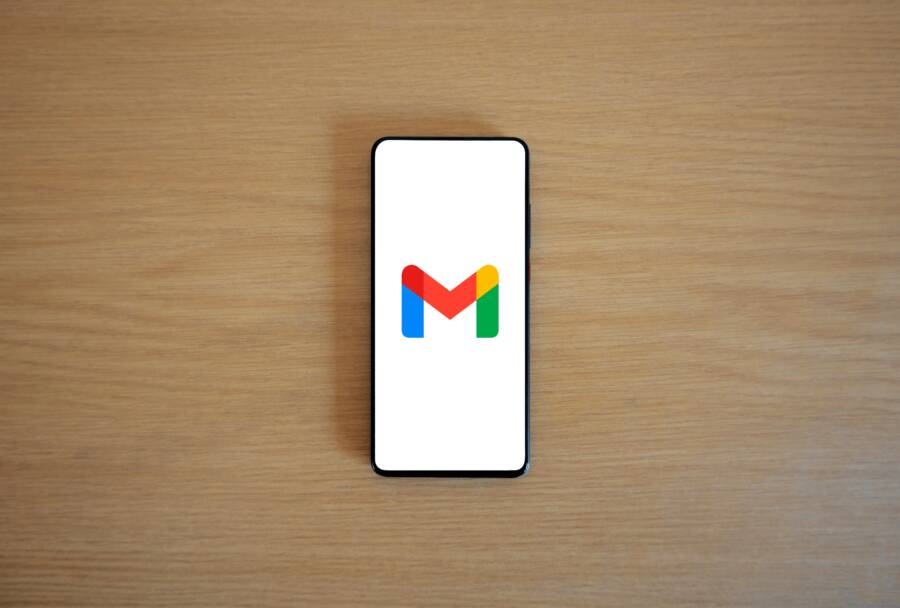 A smartphone displaying the Gmail app logo on a wooden surface, viewed from above