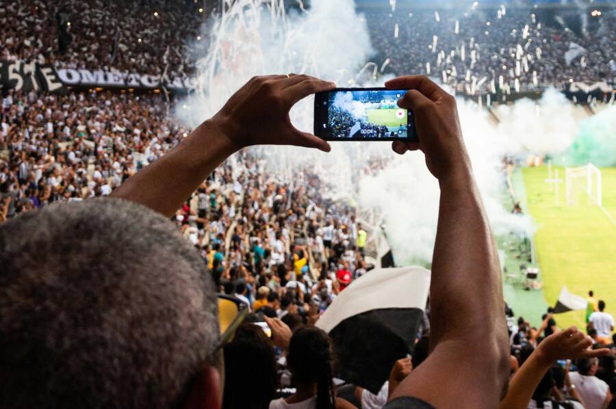 Thrilling football match scene with fans capturing the moment on a smartphone from the stadium stands