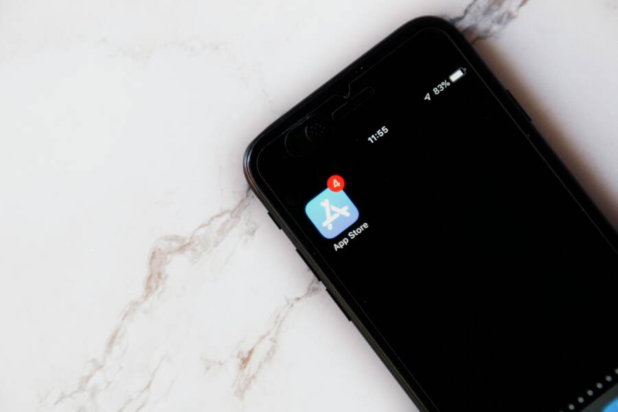 Close-up of an iPhone showing a notification on the App Store icon against a marble background