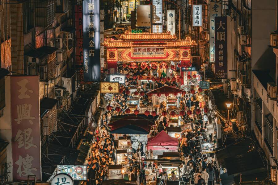 Bustling night market scene at Raohe Street, Taipei, showcasing vibrant street life and illuminated stalls.