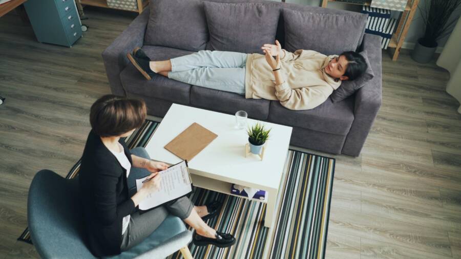 A psychotherapy session with a therapist consulting a client indoors on a sofa