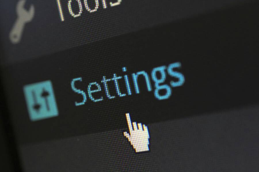 A close-up photo of a computer screen showing the settings button with a cursor hovering over it