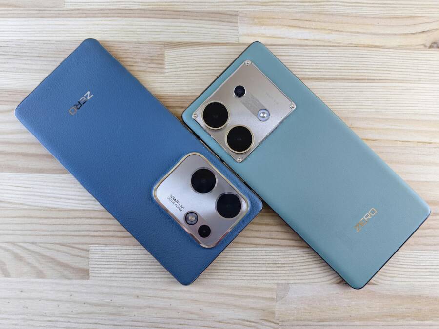 Pair of sleek smartphones with dual camera lenses on wooden background.