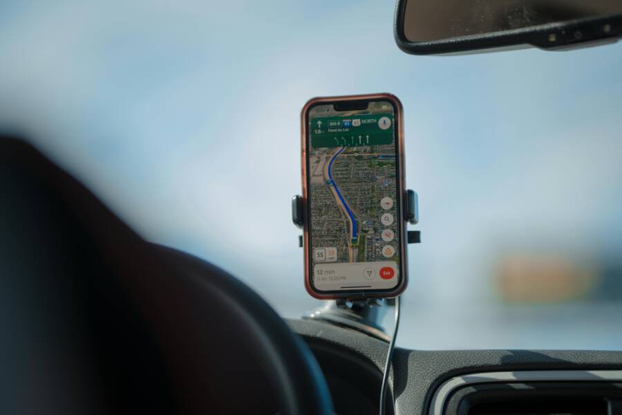 A smartphone with GPS navigation app mounted on a car dashboard during a road trip