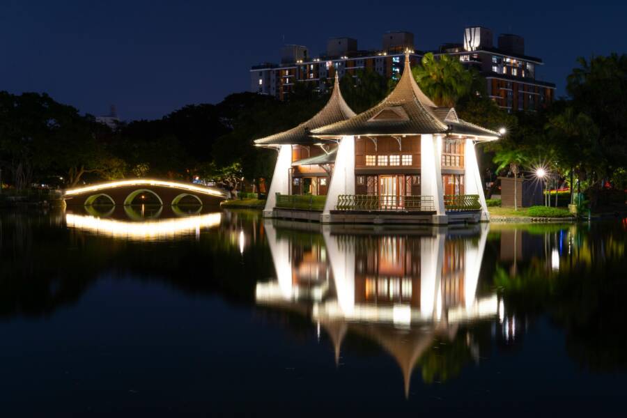 Illuminated traditional pavilion reflecting on a serene lake in Taichung City, Taiwan.
