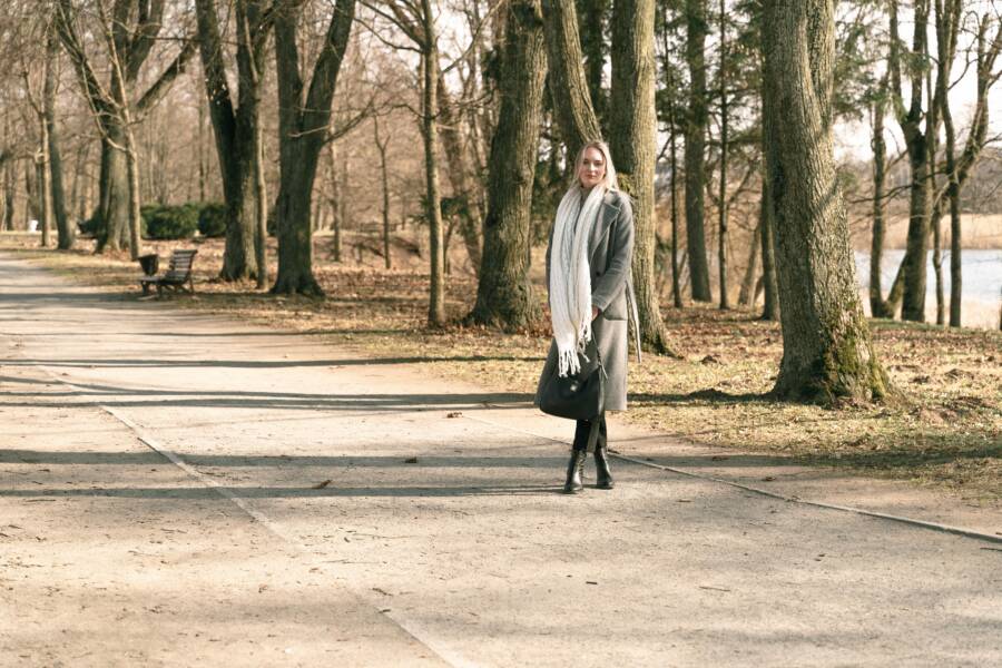 Woman walking on a sunny winter day in Niasvizh Park, Belarus, surrounded by bare trees.