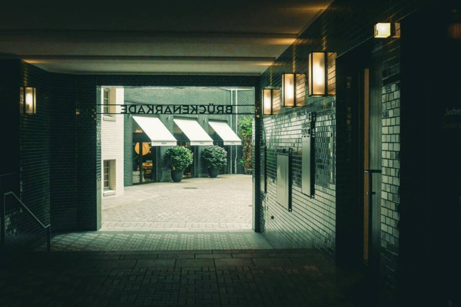 A cozy outdoor cafe seen through an urban corridor with warm lighting
