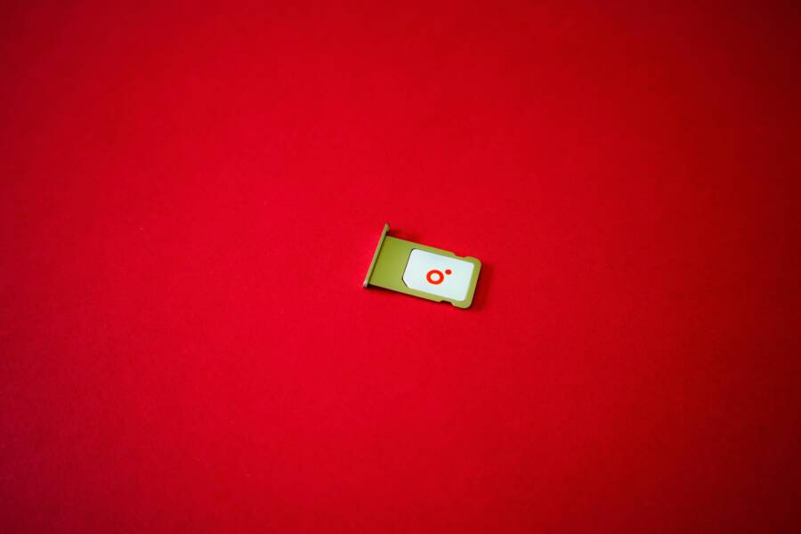 A clean image of a SIM card tray displayed on a vibrant red background.