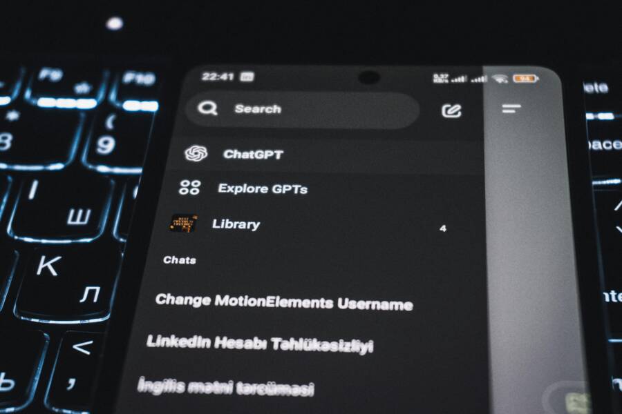Close-up of a smartphone displaying a chat app interface with a backlit keyboard in the background.