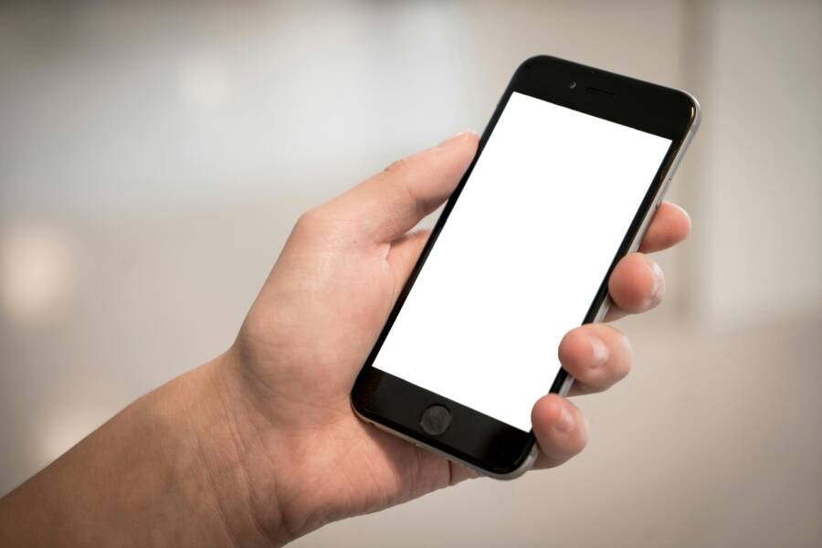 A hand holding a modern smartphone locked on a blank screen