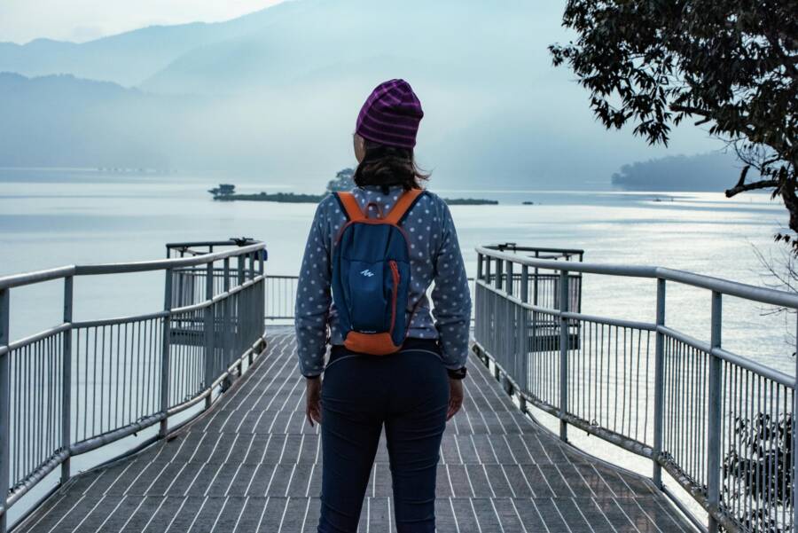 Woman with backpack on viewing platform overlooking Sun Moon Lake, Taiwan.