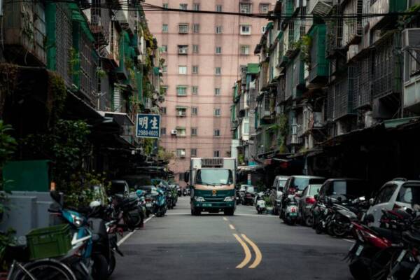 Busy urban street scene in New Taipei City, Taiwan, featuring parked scooters and a delivery truck