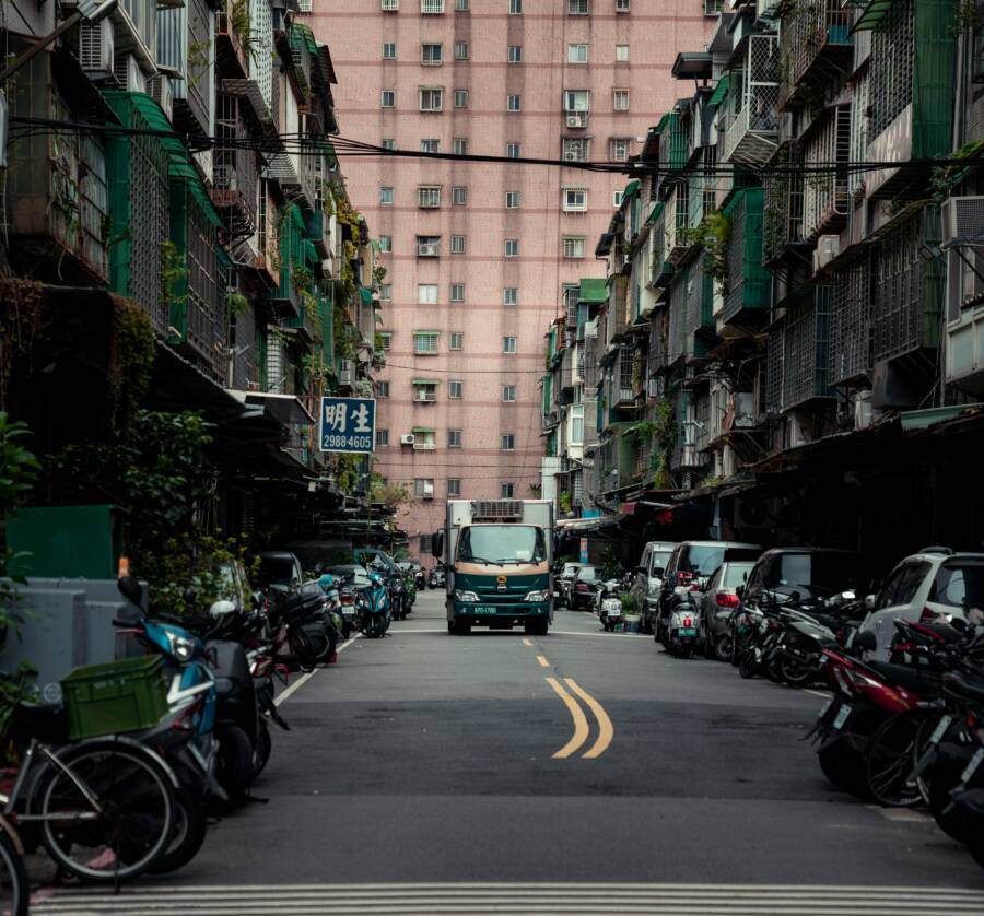 Busy urban street scene in New Taipei City, Taiwan, featuring parked scooters and a delivery truck