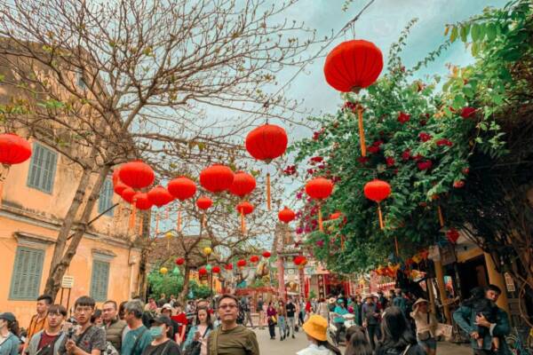 Colorful street scene with red lanterns and crowds during Lunar New Year festival.