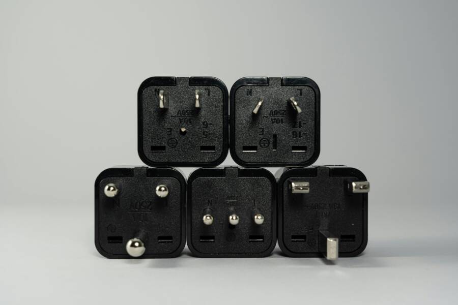 A collection of various black international power plug adapters for global electronics use