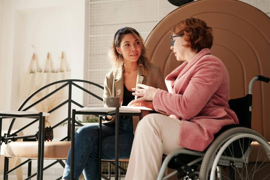 Two women in a café, one in a wheelchair, sharing a conversation