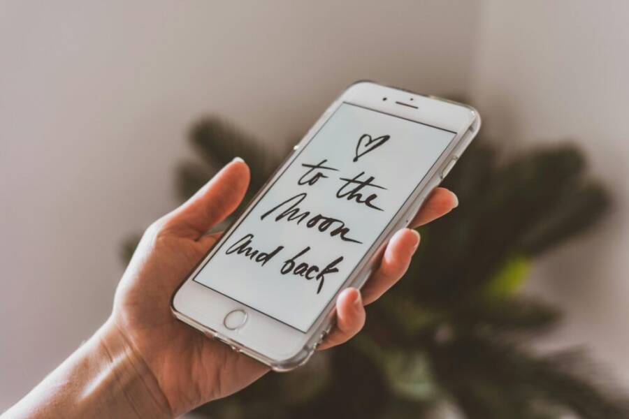A hand holding a smartphone displaying an inspirational quote