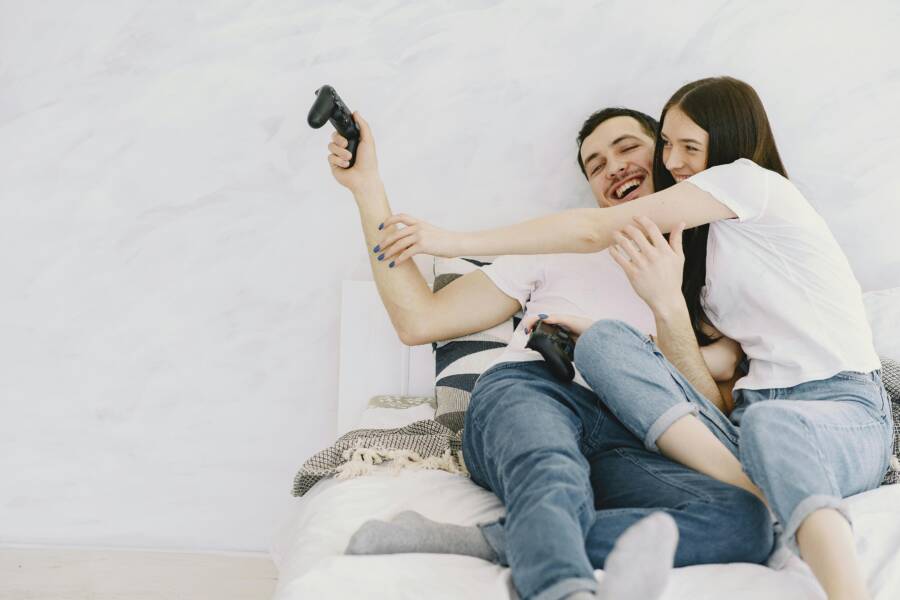 A cheerful couple having fun playing video games in bed, enjoying leisure time together