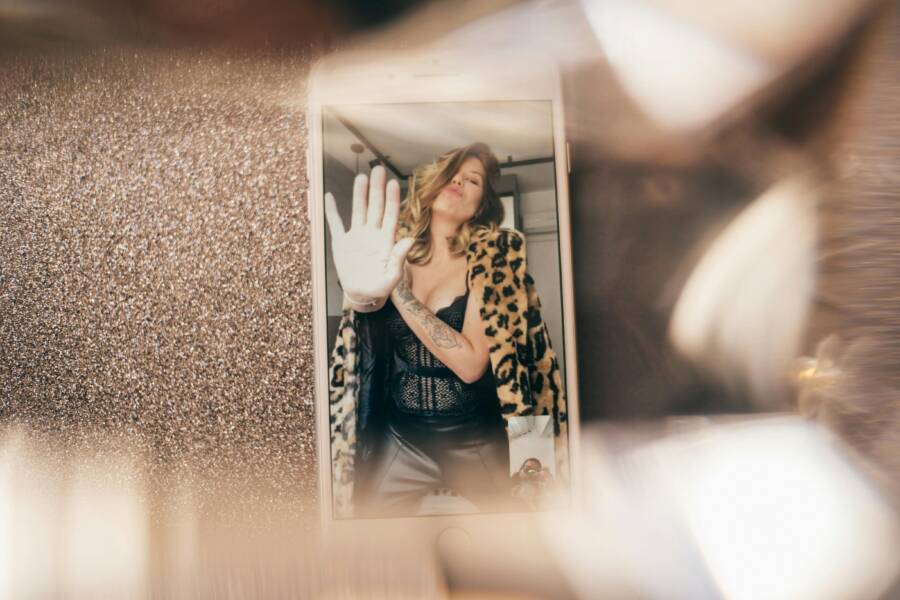 Stylish woman with leopard print coat making a gesture on smartphone screen. Modern and bold.