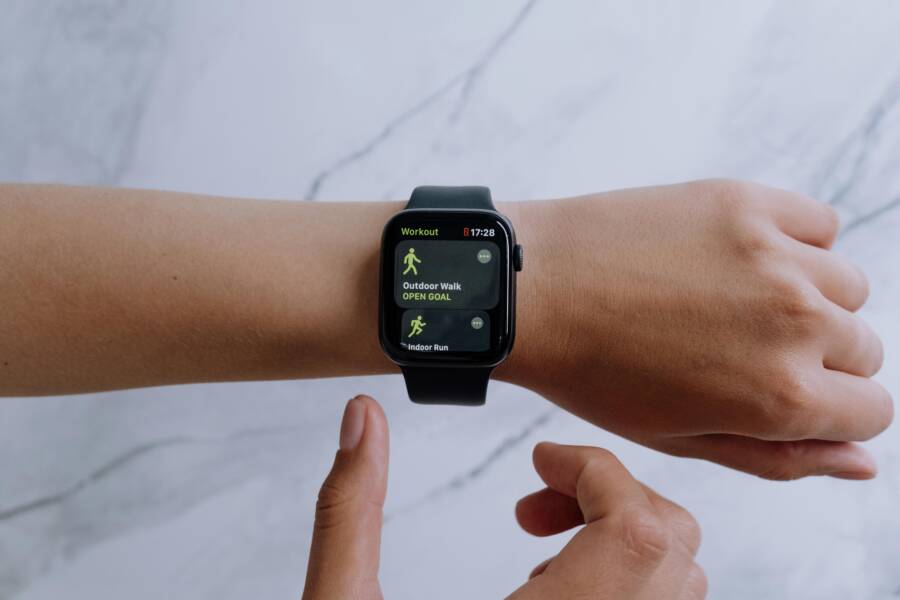 Close-up of a smartwatch on a wrist displaying health and fitness apps with a marble background.