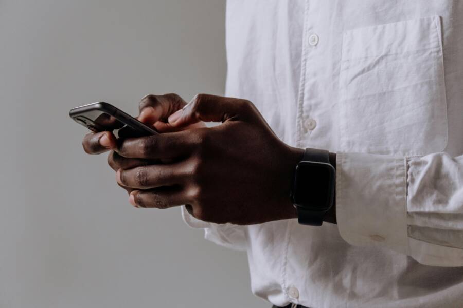 A person typing on a smartphone with a smartwatch nearby