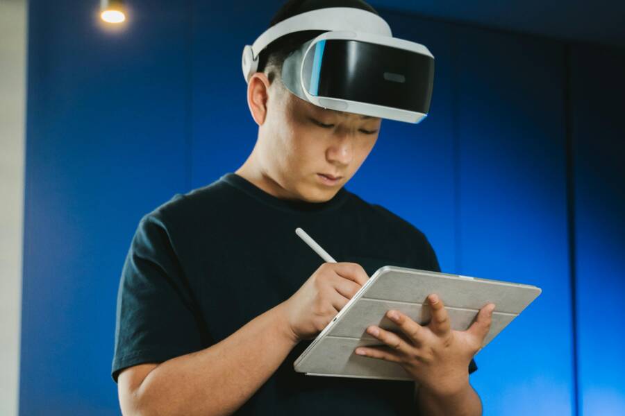 亞洲男子戴VR頭戴裝置使用平板，專注投入