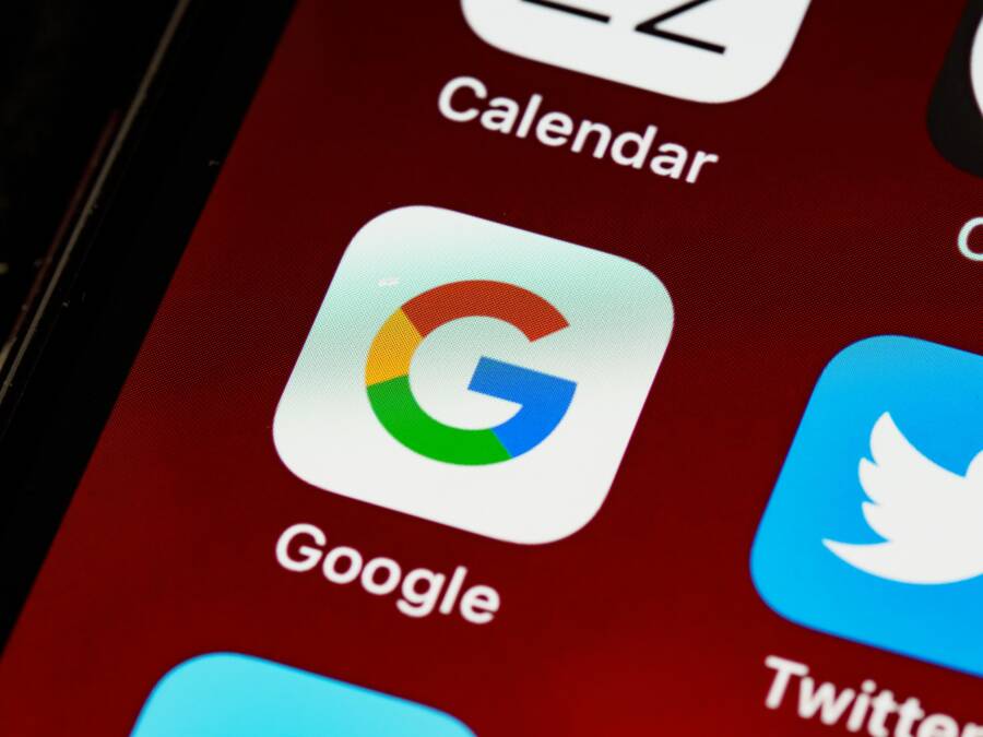 Macro view of a smartphone displaying Google and other app icons on the home screen