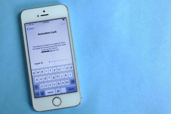 Top view of a smartphone showing activation lock screen on light blue surface