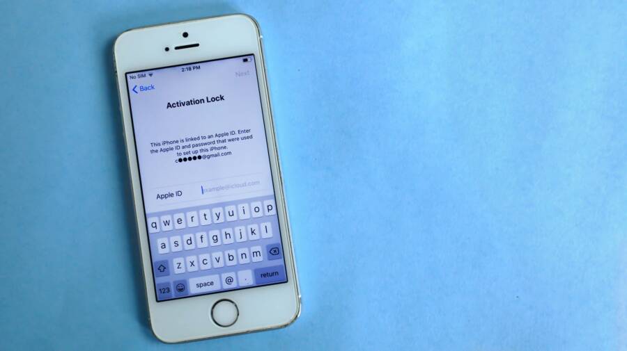 Top view of a smartphone showing activation lock screen on light blue surface.