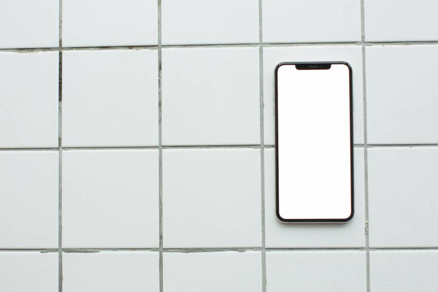 Top-down view of a smartphone with a blank screen on white tiles, ideal for mockup use
