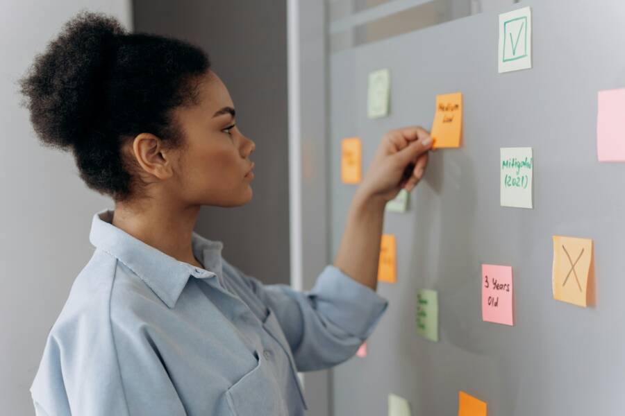 Side view of a young woman organizing colorful sticky notes on a whiteboard