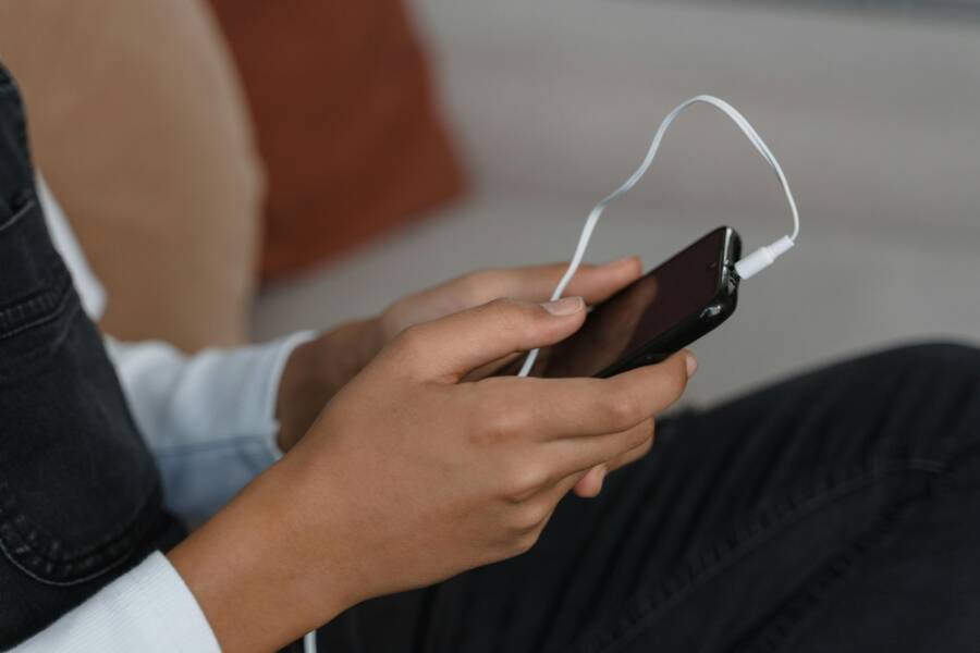 A person holds a smartphone with earbuds connected, capturing modern technology engagement