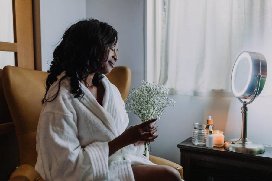 A serene morning with a woman relaxing in a robe, holding a bouquet of baby