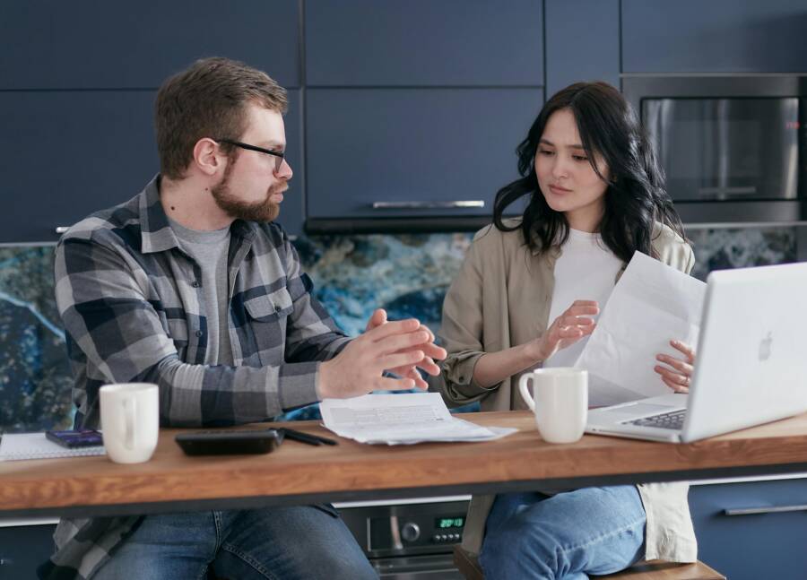 Young couple discussing financial issues with a laptop and documents in a modern kitchen.