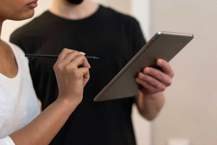 Two colleagues collaborating using a digital tablet and stylus in a modern office environment.