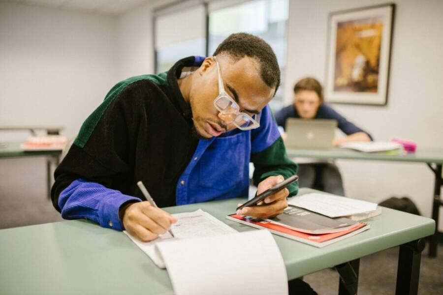 image of a student using a smartphone to take notes in a classroom