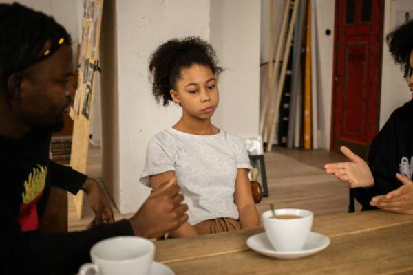 A family having a serious conversation at a table with coffee cups, highlighting a tense atmosphere indoors